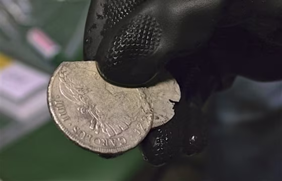 A member of Spain's Culture Ministry's technical crew displays two of the 594,000 coins and other artifacts found in the Nuestra Senora de las Mercedes, a Spanish galleon sunk by British warships in the Atlantic in 1804.